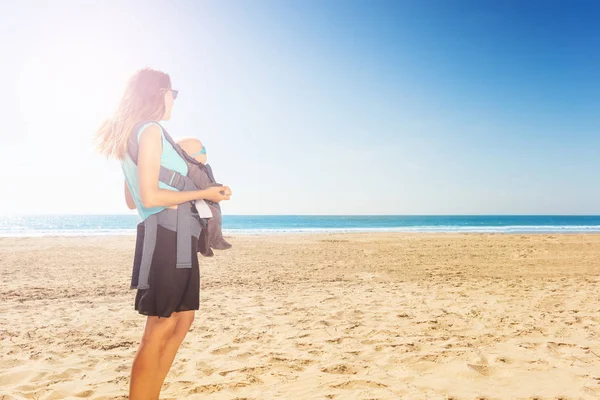 Madre llevar y mostrar bebé bebé mar infantil en la playa —  Fotos de Stock