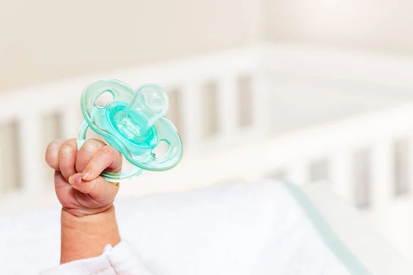 Tiny infant boy hand fist lift up holding pacifier — 图库照片