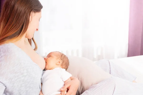 Newborn baby breastfeeding with mother sit on bed — Stock Photo, Image