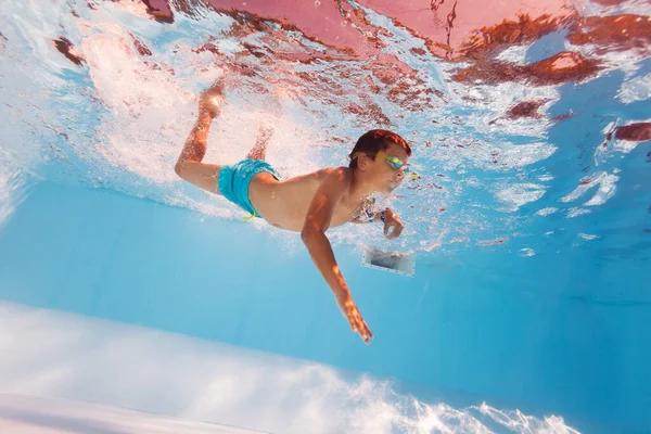 Bambino nuotare sott'acqua in piscina indossando googles — Foto Stock