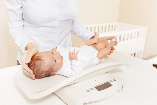 Mother measure weight infant baby boy on scale — Stok fotoğraf