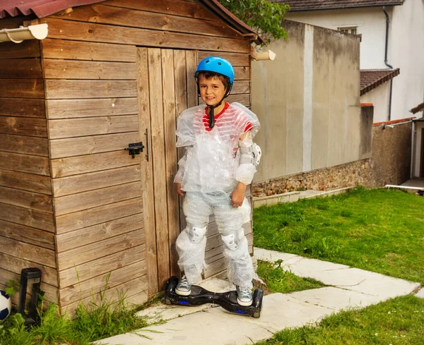 Chico montar un scooter en una envoltura de burbuja sobreprotectora — Foto de Stock