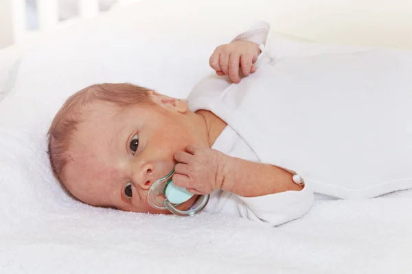 Bebê recém-nascido que coloca e segurando chupeta com a mão — Fotografia de Stock