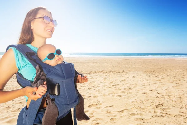 Mom carry infant baby on the sea summer beach day — Zdjęcie stockowe