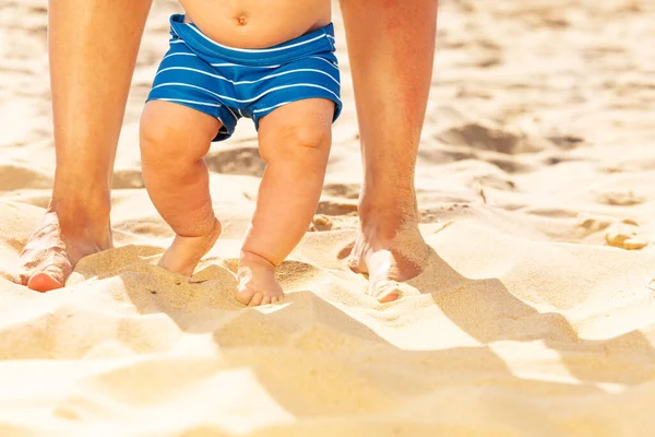 Close-up of baby and mother legs on the sand beach — Zdjęcie stockowe