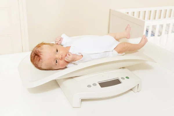 Baby boy lay on the scale to measure body weight — Stock fotografie
