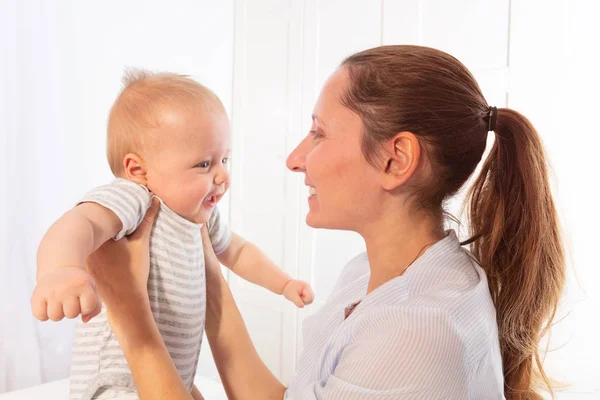 Mãe segurar bebê pequeno bebê sorrindo e falando — Fotografia de Stock