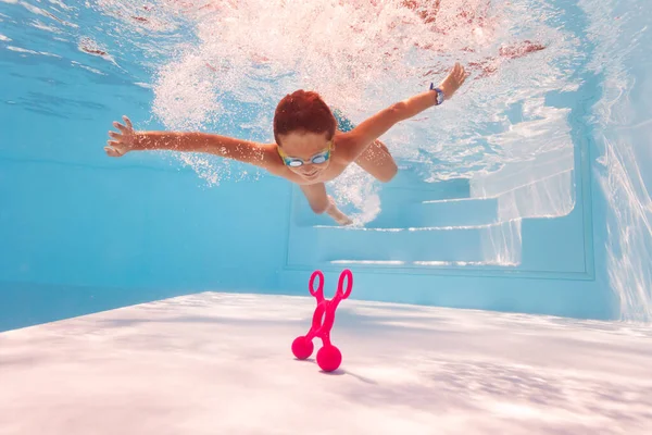 Piccolo bambino tuffo e nuotare per il giocattolo sul fondo della piscina — Foto Stock