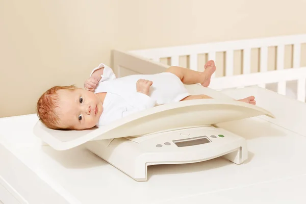 Baby boy lay on a scale for measuring body weight — ストック写真