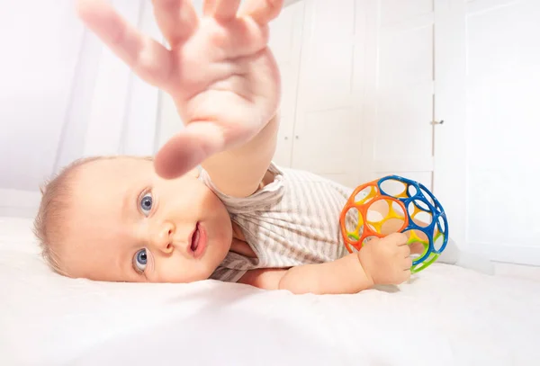 Симпатичный младенец протягивает руку и смотрит в камеру. — стоковое фото