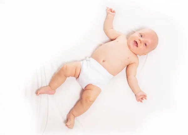 Baby infant laying on white sheet view from above — Stockfoto