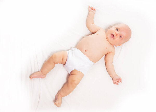 Baby infant laying on white sheet view from above