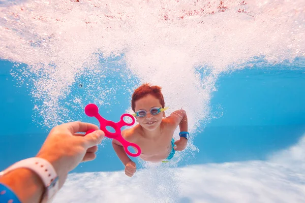 Child swim dive underwater take toy from teacher — Stockfoto