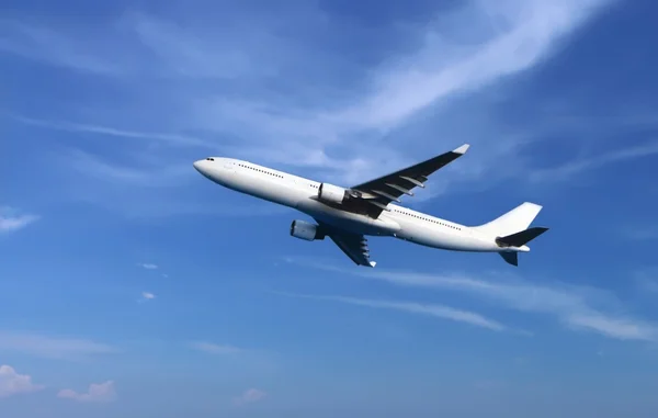 Пассажирский самолет, летящий под облачным голубым небом — стоковое фото