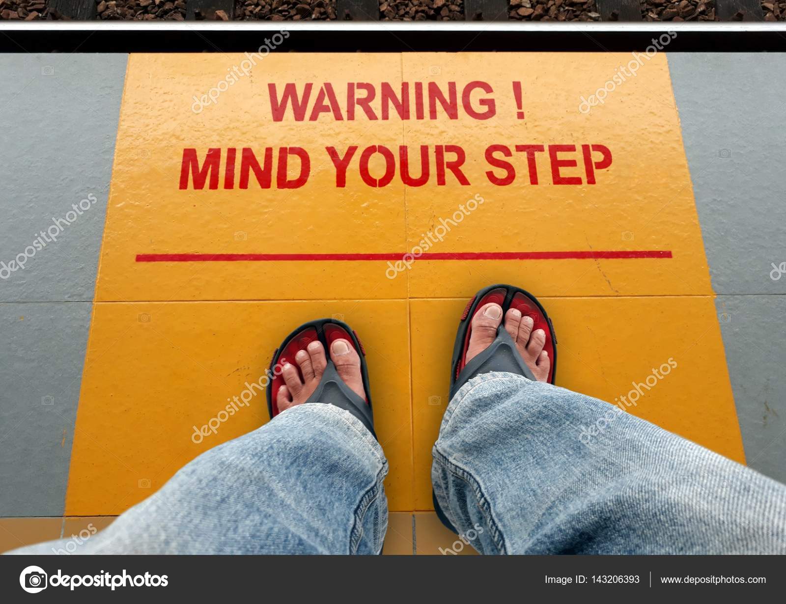 Mind Your Step Signage On A Train Platform With A Man Standing.