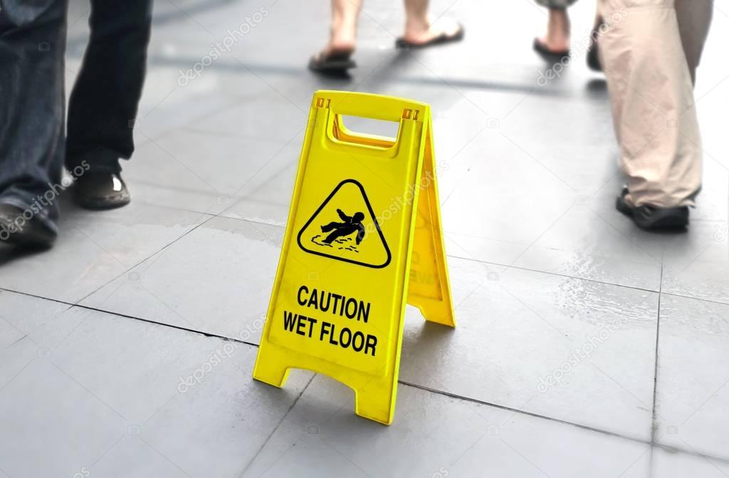 Wet floor sign with people walking in background