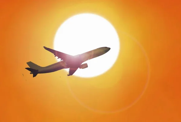 Airplane flying under sunset with yellow sky — Stock Photo, Image