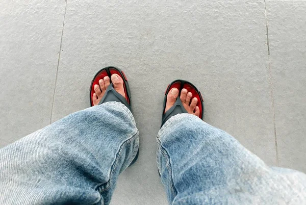Man fötter ovansida klädd i jeans och sandaler — Stockfoto