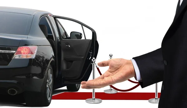 Motorista de pé com gesto de boas-vindas ao lado da limusine — Fotografia de Stock