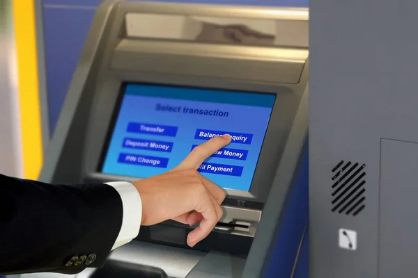 Man in suit touching display screen at ATM termina