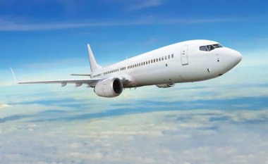 Mavi ve bulutlu gökyüzü altında uçan uçak