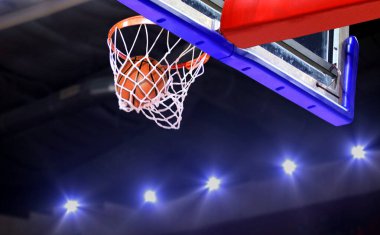 Arka planda parlak spot ışıklarıyla potaya basket atışı