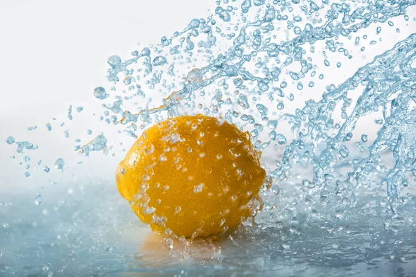 Limão com respingo de água azul — Fotografia de Stock