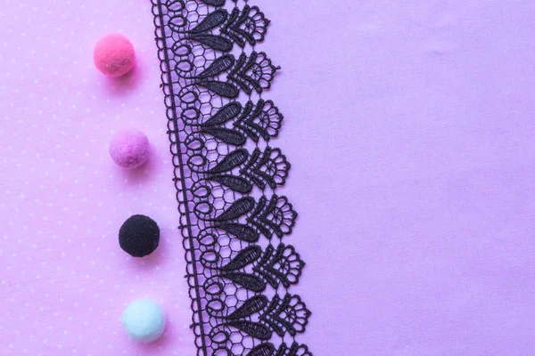 Tecido roxo e renda preta. Fundo com tecido e renda artesanal. Pele bolas branco preto rosa roxo . — Fotografia de Stock