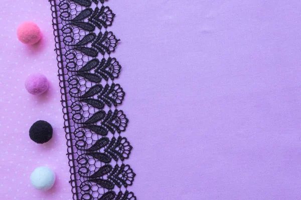 紫色面料和黑色蕾丝。织物和手工花边的背景。毛球白色黑色粉红色紫色. — 图库照片