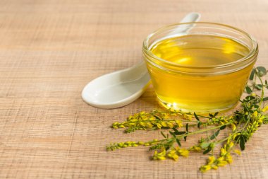 Cam fincan bal ve kır çiçekleri ile ahşap bir masa üzerinde bir sarı yonca ile.