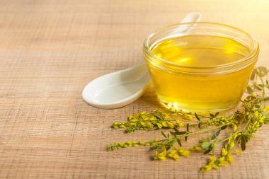 Cam fincan bal ve kır çiçekleri ile ahşap bir masa üzerinde bir sarı yonca ile.