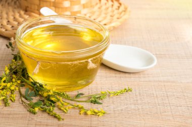 Cam fincan bal ve kır çiçekleri ile ahşap bir masa üzerinde bir sarı yonca ile.