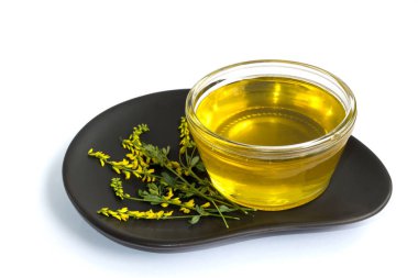 Cam Kavanoz renkler sarı yonca ile beyaz bir arka plan üzerinde siyah bir tabakta bal ile.