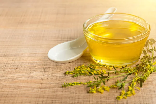 Cam fincan bal ve kır çiçekleri ile ahşap bir masa üzerinde bir sarı yonca ile.