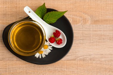 Bir fincan tabak tatlım. Kaşık bal, ahududu, papatya, derevyanny arka plan damla.