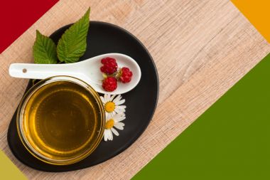 Bir fincan tabak tatlım. Kaşık bal, ahududu, papatya, derevyanny arka plan damla.