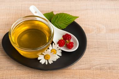 Bir fincan tabak tatlım. Kaşık bal, ahududu, papatya, derevyanny arka plan damla.