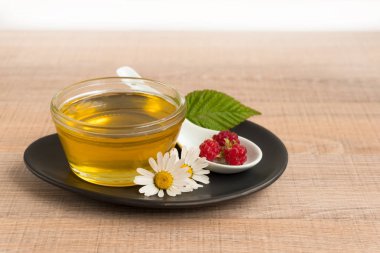 Bir fincan tabak tatlım. Kaşık bal, ahududu, papatya, derevyanny arka plan damla.