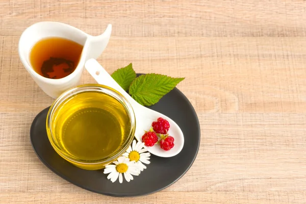 Bir fincan tabak tatlım. Kaşık bal, ahududu, papatya, derevyanny arka plan damla.