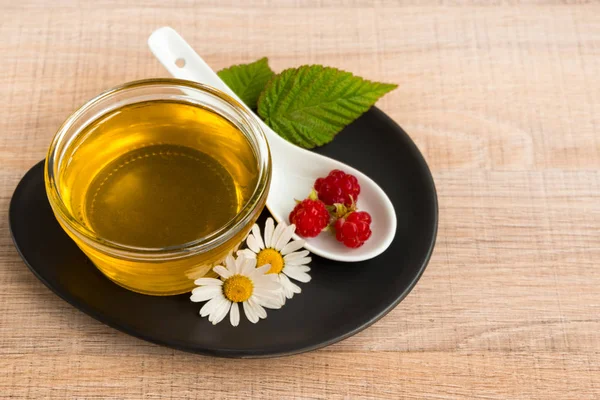 Bir fincan tabak tatlım. Kaşık bal, ahududu, papatya, derevyanny arka plan damla.