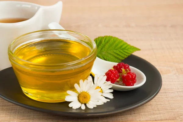 Bir fincan tabak tatlım. Kaşık bal, ahududu, papatya, derevyanny arka plan damla.