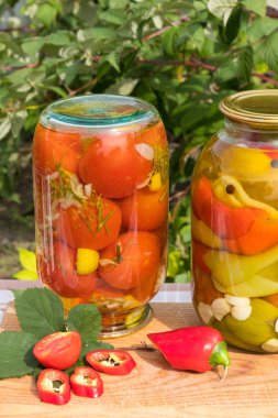 Bankalar konserve domates ve biber yağı ile. Bahçe arka plan üzerinde.