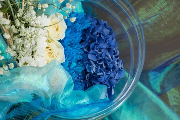 蓝色和绿色的花朵淹没在一个玻璃瓶里的水中。水滴, 气泡. — 图库照片