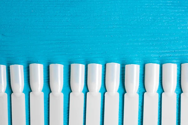 White plastic templates for nail Polish varnish. On a blue wooden table. — Stock Photo, Image