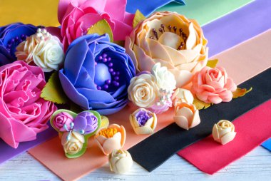 Foamiran çiçekler. El yapımı çiçekler. İşlenecek parçanın malzeme. Ahşap arka plan üzerinde.