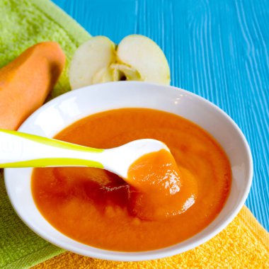 bir ahşap masa kaşık uçan daire Beyaz yeşil emzik peçete portakal bebek havuç elma püresi