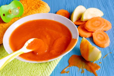 bir ahşap masa kaşık uçan daire Beyaz yeşil emzik peçete portakal bebek havuç elma püresi