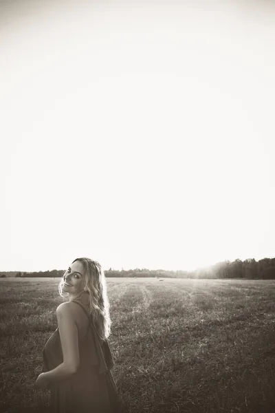 Bir alanda gün batımında poz kız — Stok fotoğraf
