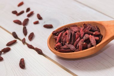 Beyaz zemin üzerinde bir tahta kaşık Goji meyveleri.