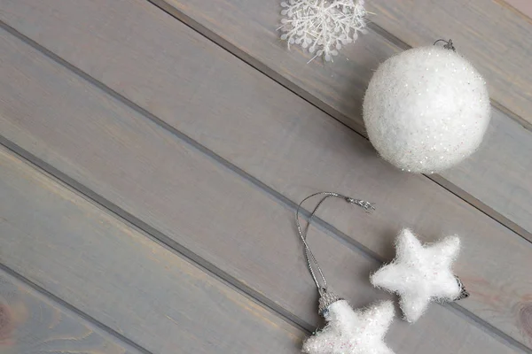 Kerst ornamenten in wit op een lichtgrijze houten achtergrond. New Year's accessoires. Van bovenaf bekijken. — Stockfoto